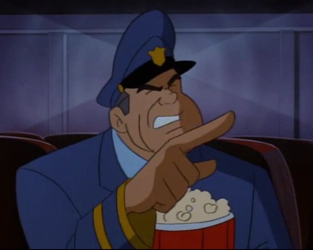 Cosgrove, a burly police sergeant from the cartoon Freakazoid, points accusingly off camera. He holds a bucket of popcorn in his other hand.